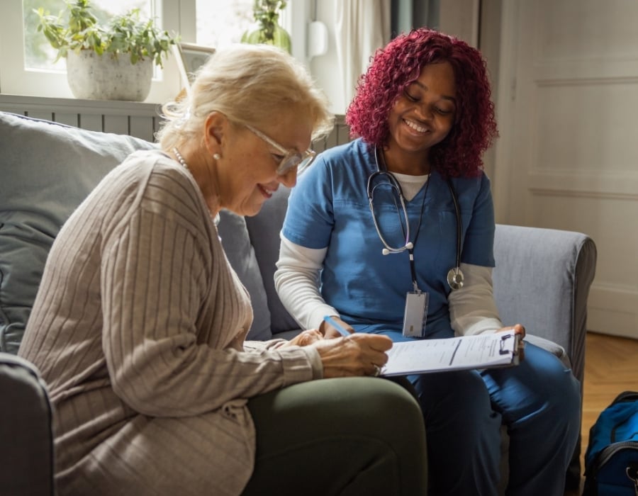 Elderly woman reviewing documentation with a home health caregiver.